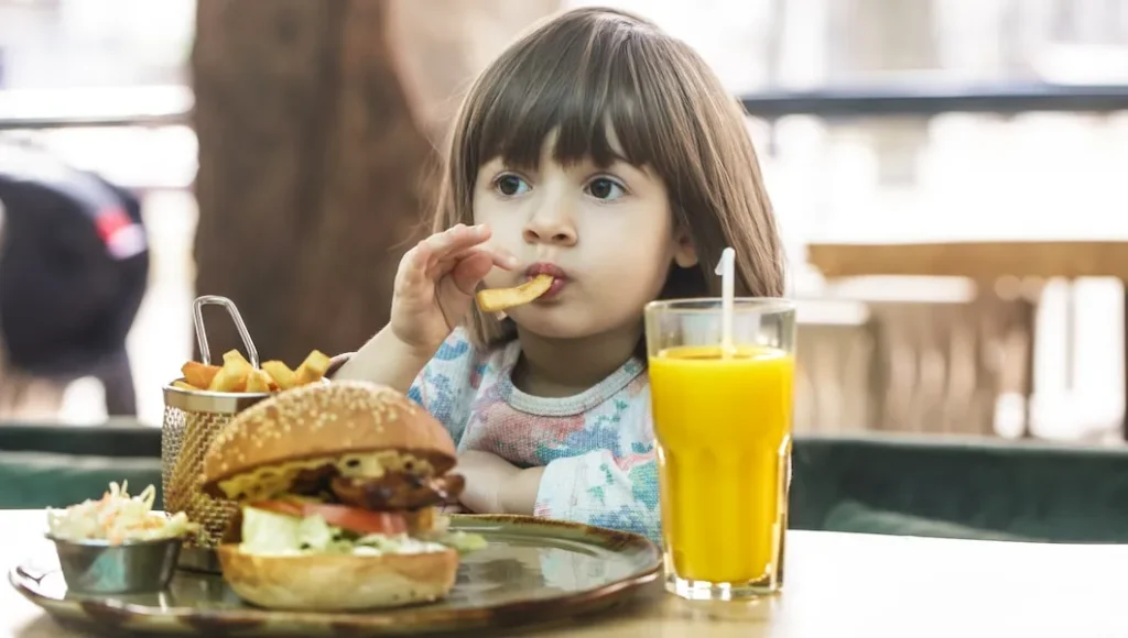 Little girl eats in a fast food cafe